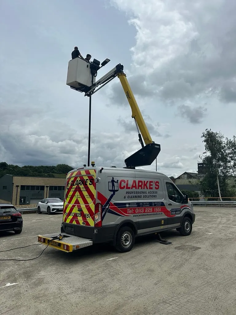 Cherry picker cleaning cladding on an industrial unit